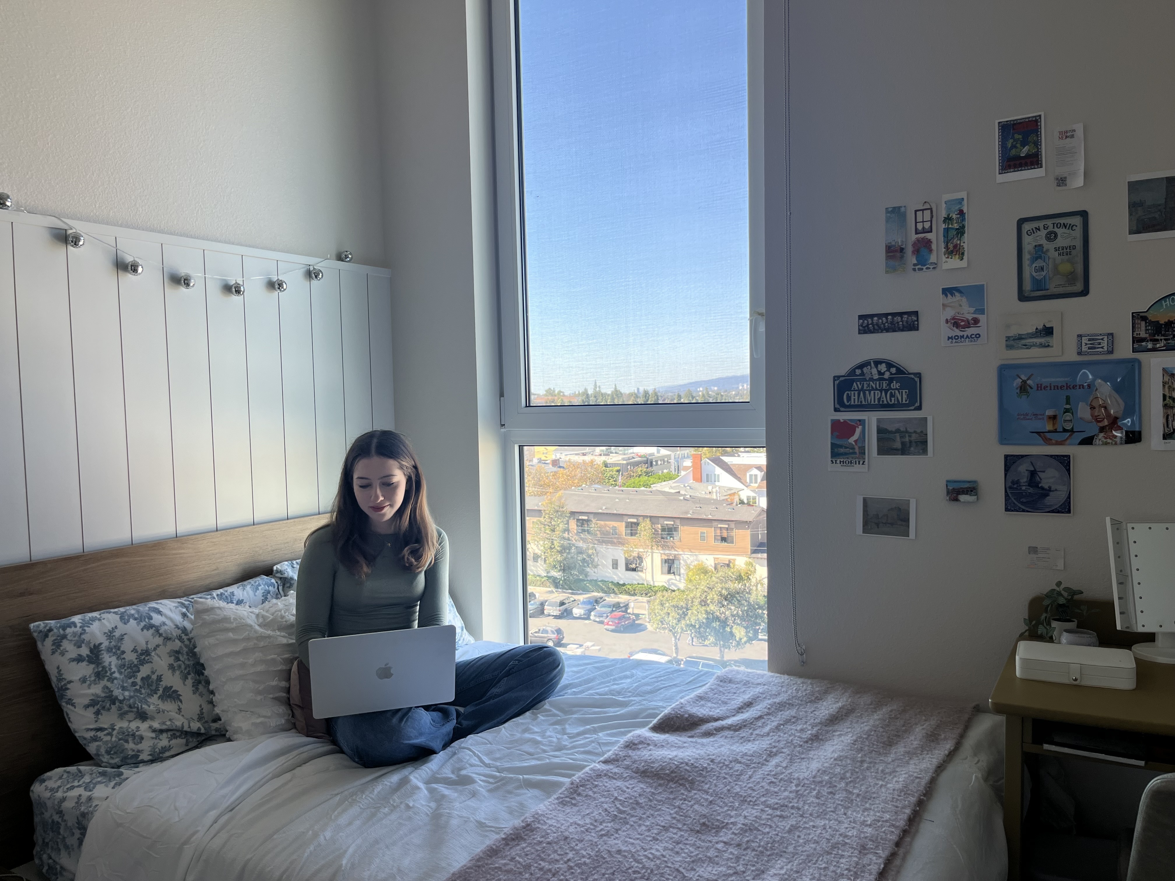 A photo of Tori Feinstein sitting on her bed in her apartment.