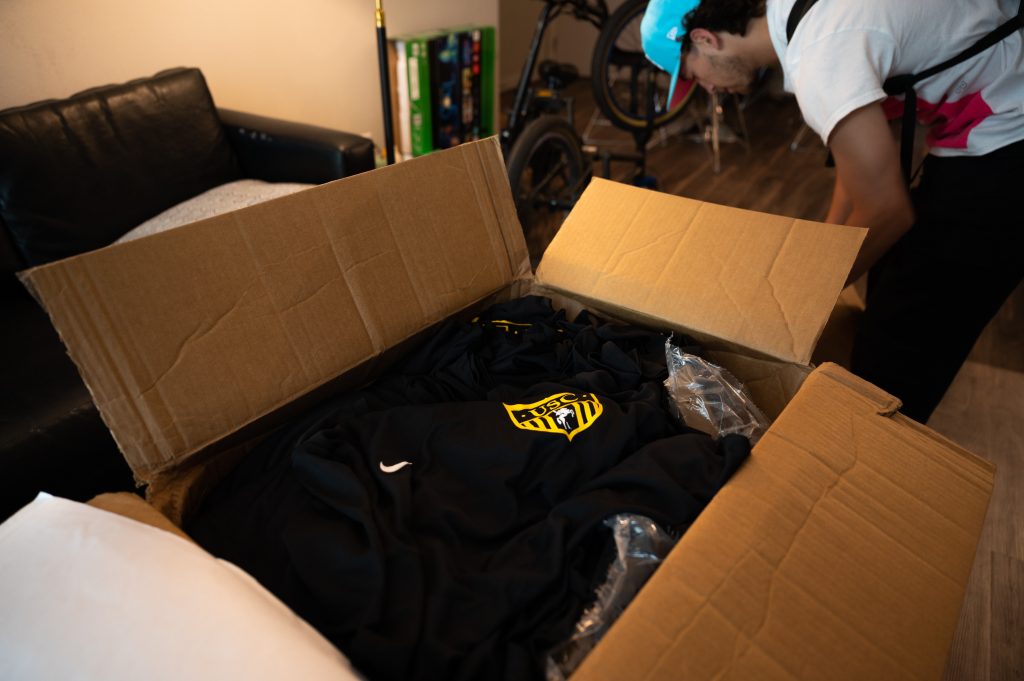A man opens a box to reveal jerseys.
